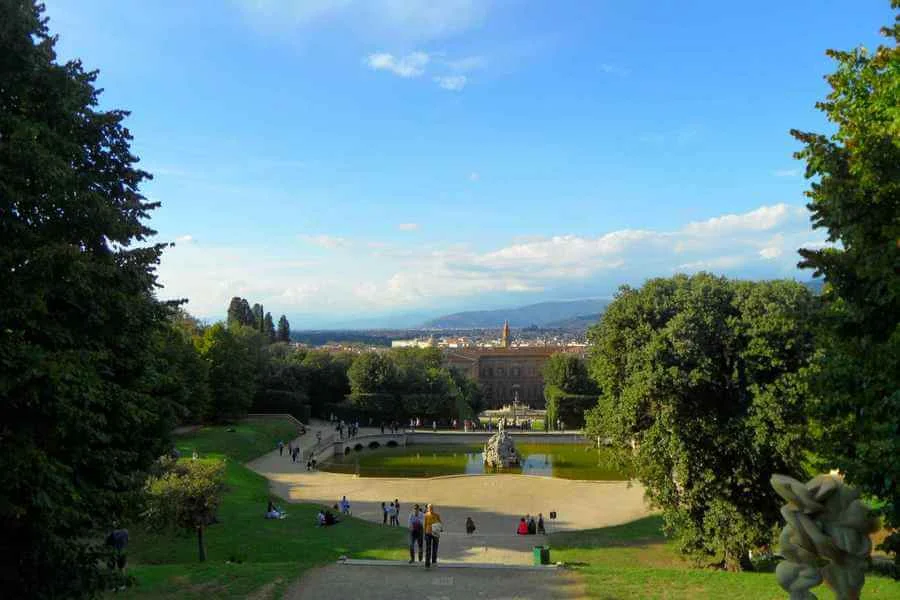 Tree lined path in Boboli Gardens down to lake with fountain and views to Pitti Palace, Florence.