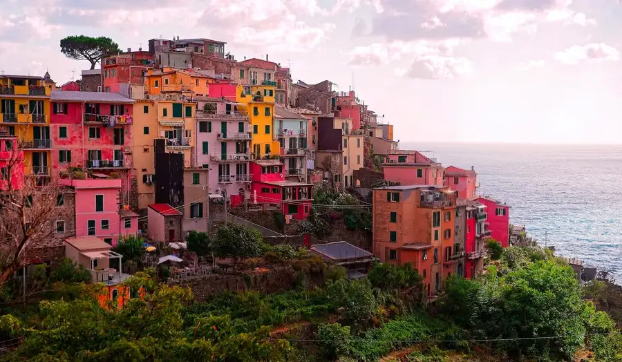 The colourful houses of Corniglia village overlooking the sea at sunset.