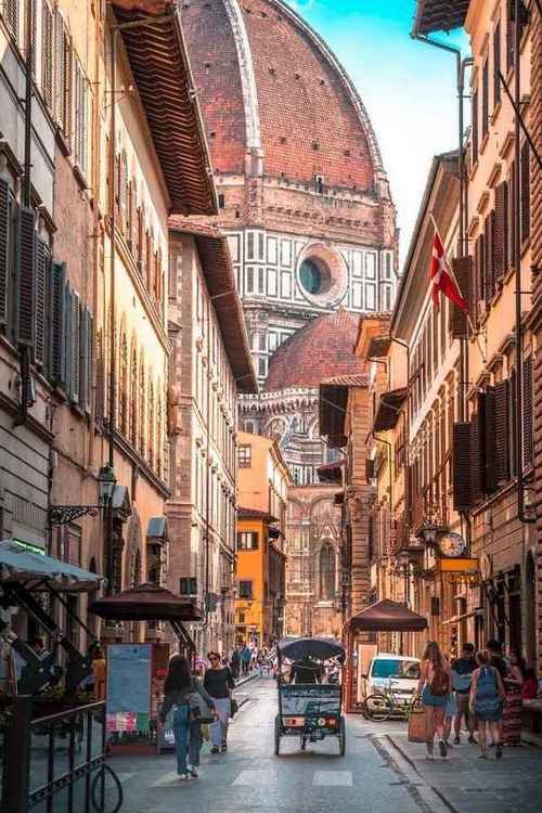 Monumental Florence Cathedral at end of a narrow medieval street in historic city centre.