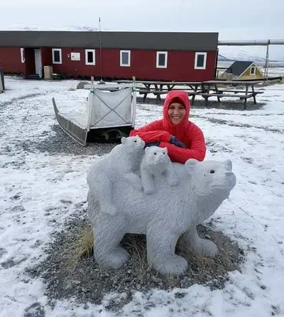 Kristen in the snow by a polar bear scupture in front of Old Camp Hostel in Kangerlussuaq.