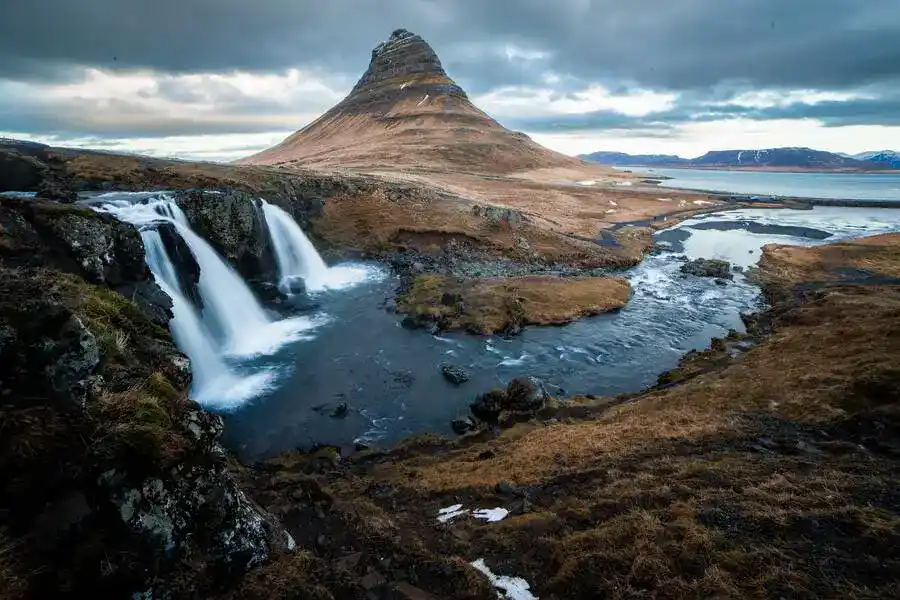 Cone-shaped Kirkjufell mountain and the waterfalls gushing to the ocean.