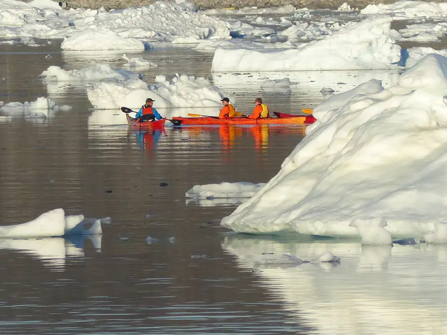Bright orange canoes among icebergs in Ilulissat ice field.