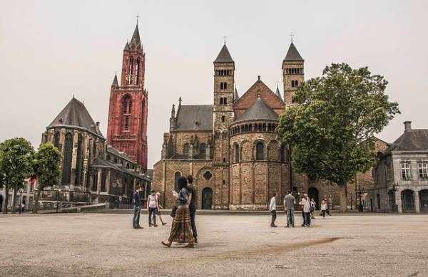 People walking past historical buildings in Maastrich square.