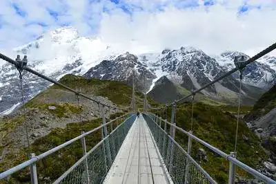 Swingbridge over the Hooker Valley with snowy mountains in the distance.