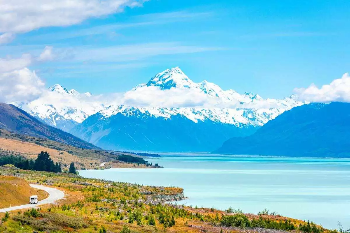 Campervan on a New Zealand South Island road trip itinerary by a lake and mountains.