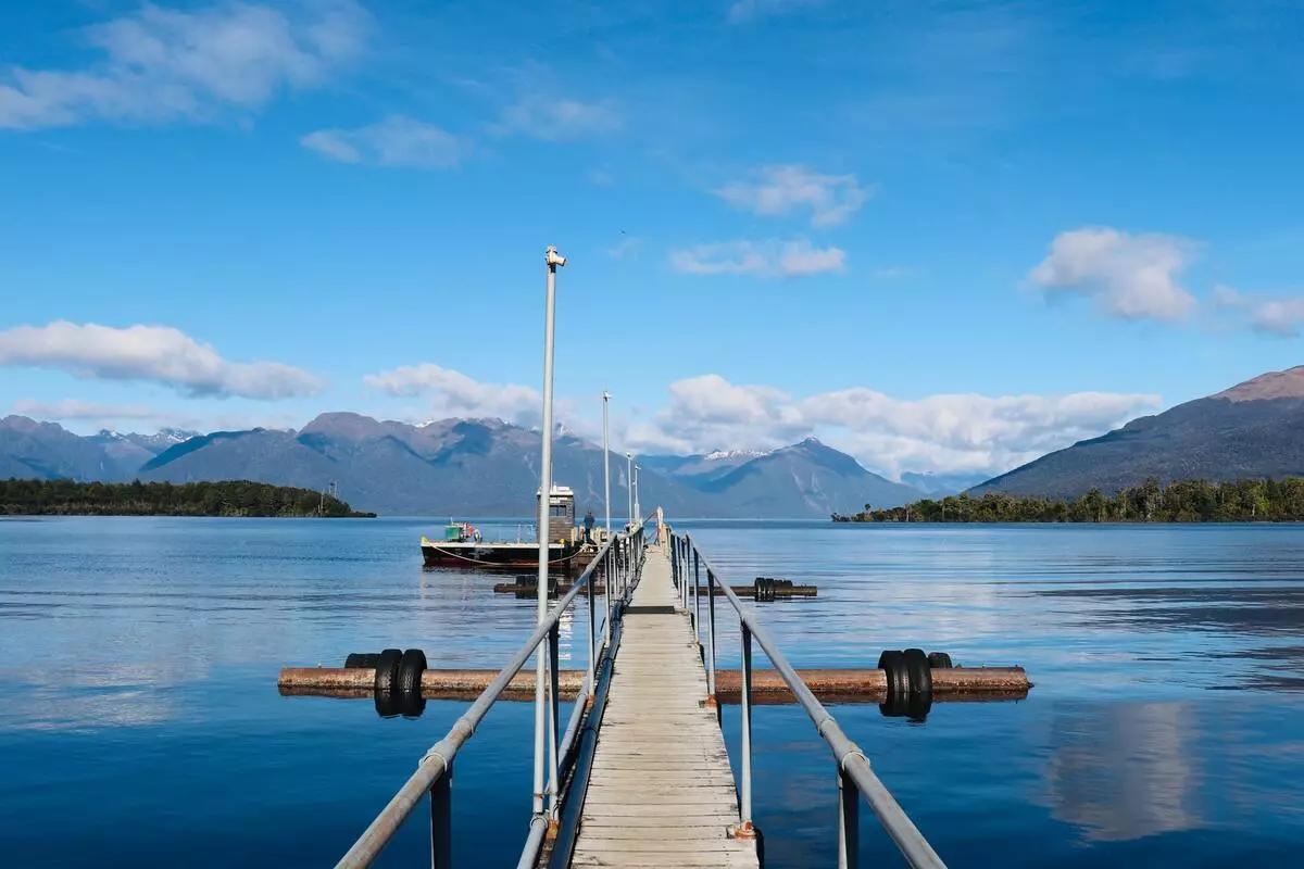 Boardwalk pier jutting into lake with mountains in the distance.