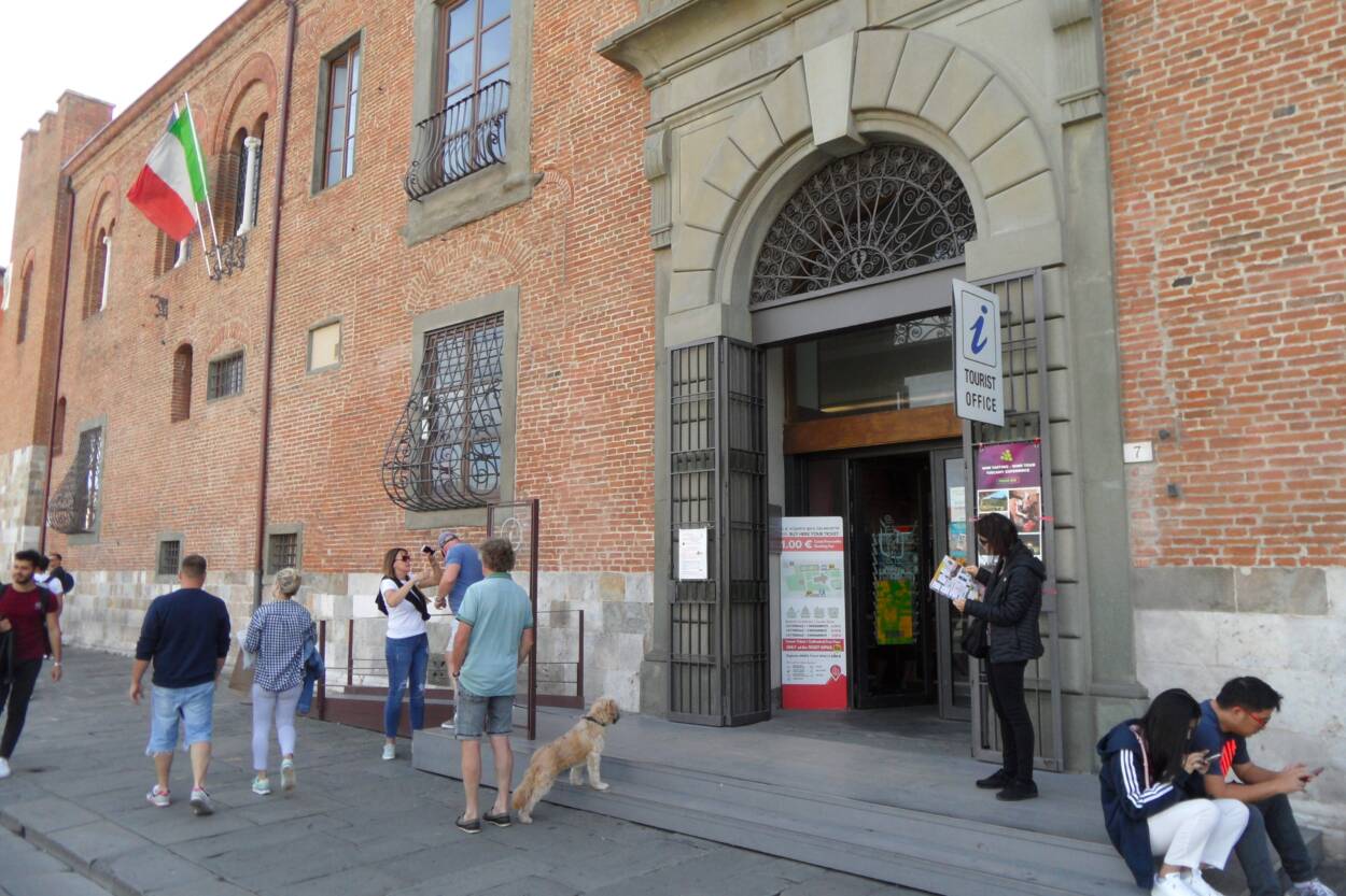 Visitors and a pet dog outside the brick façade tourist office.