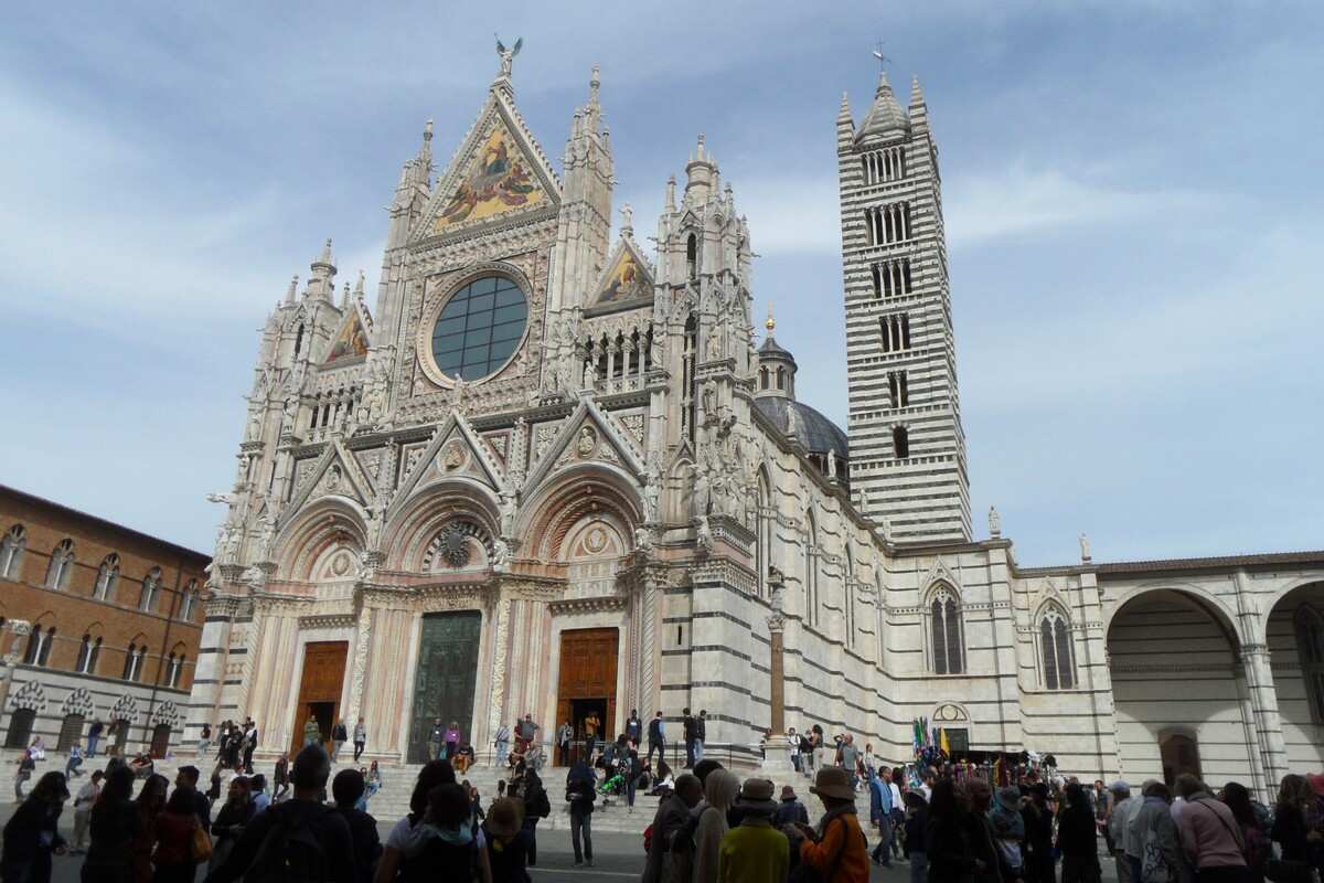 Tourists outside the ornate marble Gothic Cathedral on a walking tour of Siena.