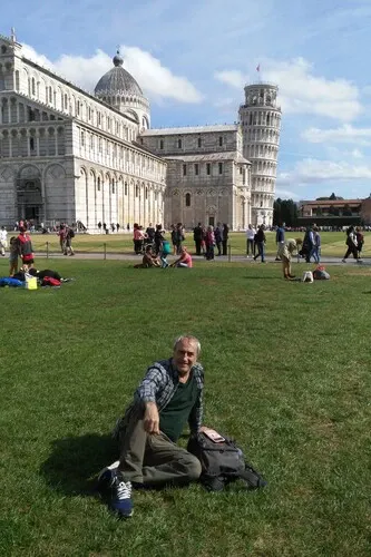 Man sitting on the lawn in front of the leaning tower.
