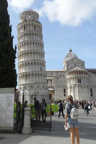 Girl standing at the gateway facing the leaning tower and cathedral.