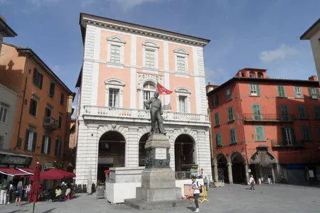 Statue in front of a pink historical building.