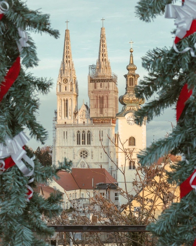 View of Zagreb cathedral from a balcony framed by Christmas trees.